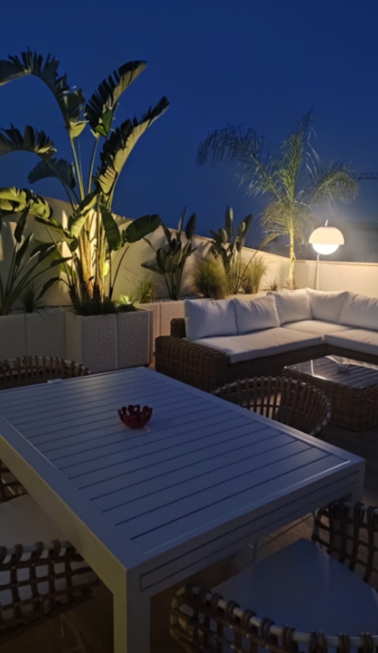 Salotto sul terrazzo con fioriere bianche e luci